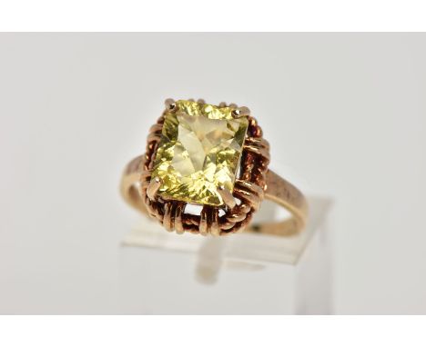 A 9CT GOLD DRESS RING, designed with a claw set rectangular cut stone assessed as citrine, rope twist style surround, plain p