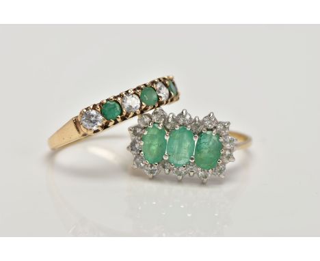 TWO 9CT GOLD EMERALD AND CUBIC ZIRCONIA RINGS, the first designed as a row of three oval cut emeralds within a cubic zirconia