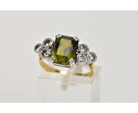 AN 18CT GOLD TOURMALINE AND DIAMOND DRESS RING, centring on an emerald cut green tourmaline, flanked with six round brilliant