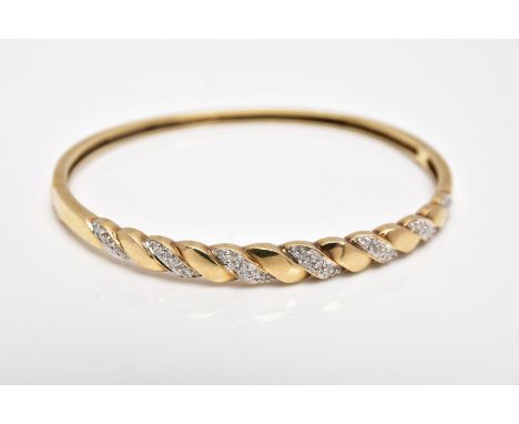 A 9CT GOLD DIAMOND SET HINGED BANGLE, of twist design, set with diagonal sections of single cut diamonds to the front half, a
