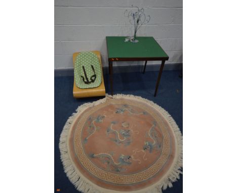 A WOOLLEN CHINESE PINK CIRCULAR RUG, diameter 127cm along with a folding bridge table, a bloom coco cantilever baby lounger, 