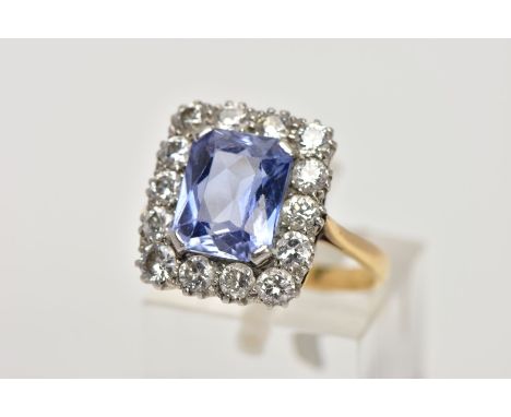 A MID TO LATE 20TH CENTURY SAPPHIRE AND DIAMOND CLUSTER RING, an emerald cut purplish blue sapphire, measuring approximately 