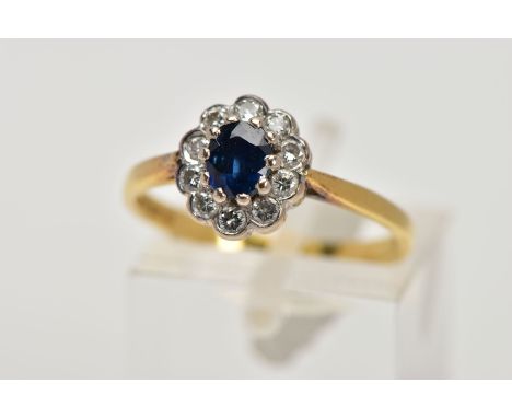 AN 18CT GOLD SAPPHIRE AND DIAMOND CLUSTER RING, the central oval sapphire in a ten claw setting within a collet set brilliant