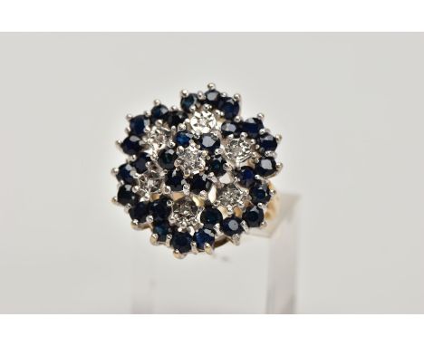 A 9CT GOLD SAPPHIRE AND DIAMOND CLUSTER RING, the tiered cluster claw set with circular blue sapphires and single cut diamond