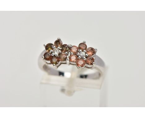 A 9CT WHITE GOLD CLUSTER RING, designed with two flower shaped clusters, each set with a central colourless stone assessed as