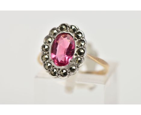 A 9CT GOLD AND SILVER CLUSTER RING, centring on an oval cut pink stone assessed as paste, within a marcasite surround, tapere