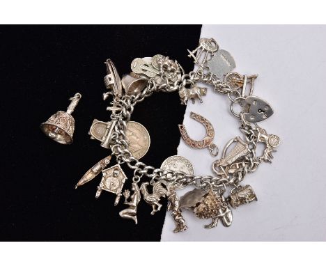 A SILVER CHARM BRACELET AND TWO LOOSE CHARMS, the charm bracelet fitted with twenty-six charms in forms such as bagpipes, tob