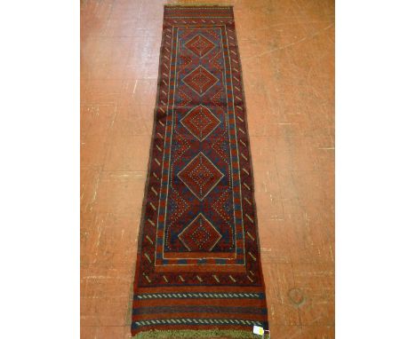 A MESHWANI CARPET RUNNER, blue and red ground with repeating central diamond pattern and double border, 247 x 59 cms