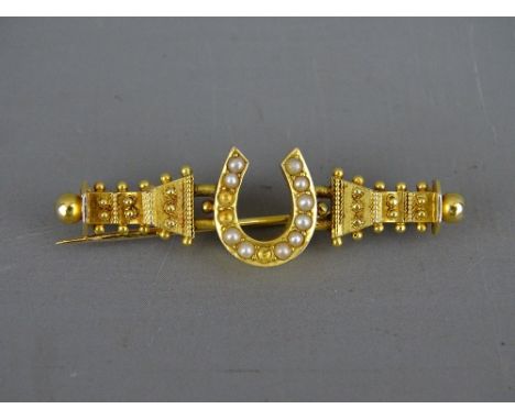 A FIFTEEN CARAT GOLD BROOCH with seed pearl encrusted horseshoe, 4 grms