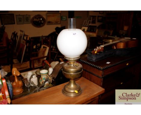 A brass oil lamp with opaque shade 
