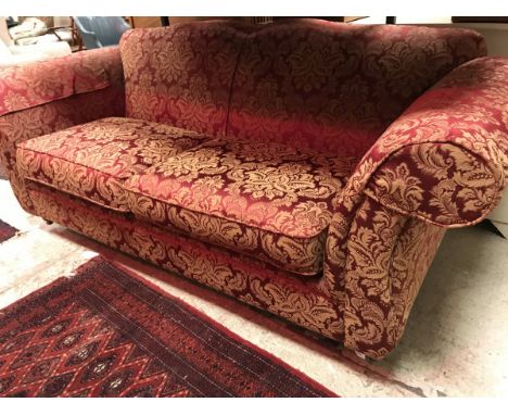 A modern upholstered scroll-arm shaped back sofa with gold floral on red upholstery