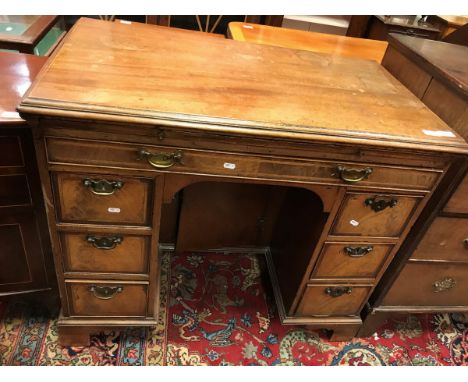 An 18th Century mahogany kneehole desk the top with molded edge above a slide with tooled writing surface over a slim drawer 