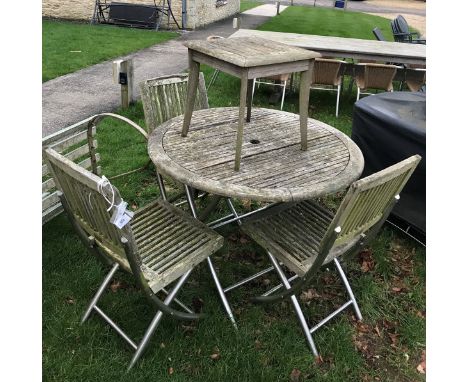 A teak garden table with three chairs and a stool