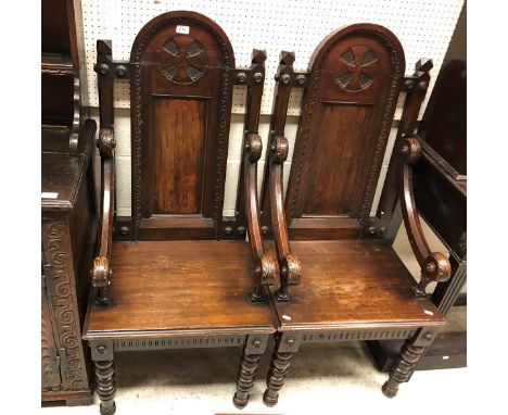 A pair of late 19th Century continental stained pine throne type hall chairs the arched panelled backs with Maltese cross typ