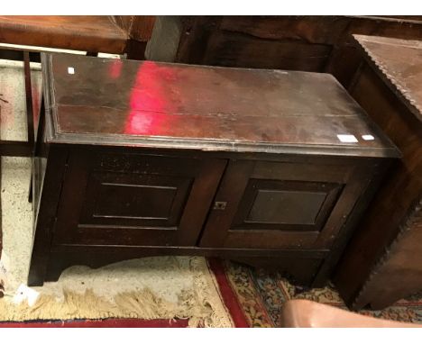 An 18th Century oak coffer of small proportions the rising top with molded edge over two panel front now as cupboard doors en