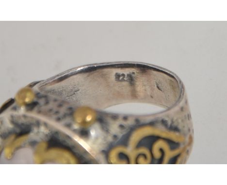 A vintage 925 silver ring set with a large oval faceted rose quartz with yellow metal granulation and fretwork decoration. . 