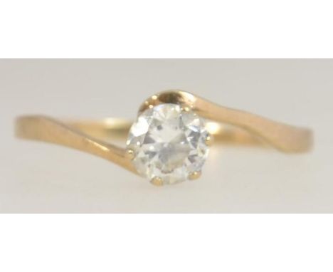 A hallmarked 9ct gold ring with a large prong set clear stone approx 25pts on a cross over band. Hallmarked for London. Size 