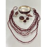 A suite of vintage garnet jewelry including a gilt metal graduated five row stiff hinged bangle, one