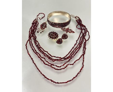 A suite of vintage garnet jewelry including a gilt metal graduated five row stiff hinged bangle, one stone replaced, ( D x 6 