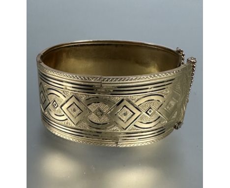 A Middle Eastern yellow metal engraved cuff style hinged bangle with traces of black enamel, a/f. 36.6g