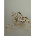 A Edwardian 9ct gold floral spray brooch set seed pearls complete with safety chain, (L x 6.5cm)