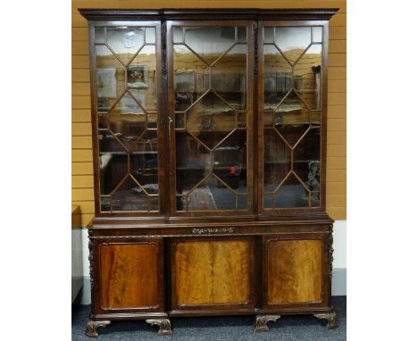 FINE WARING &amp; GILLOW MAHOGANY BREAKFRONT BOOKCASE, foliate carved cavetto cornice above astragal glazed doors between aca