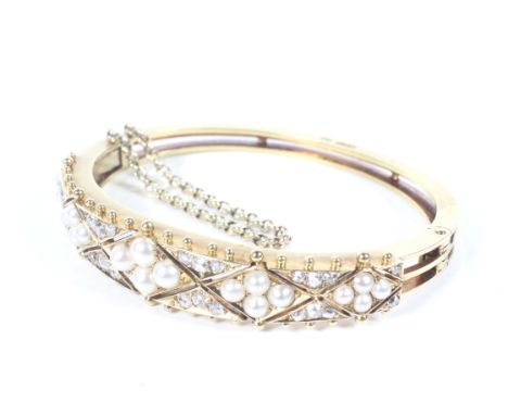 A late Victorian gold, half-pearl and diamond hinged bangle. The pierced front in the form of five graduated half-pearl lozen