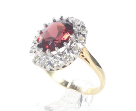 A mid-20th century gold, garnet and diamond oval cluster ring. Centred with an oval mixed-cut almandine garnet, claw set with