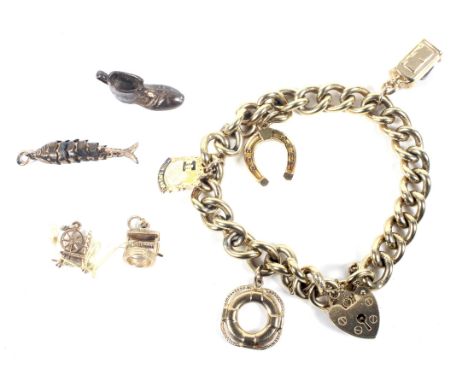 A vintage 9ct gold curb link 'charm' bracelet. On a heart-shaped padlock clasp with hallmarks for London 1972, and hung with 