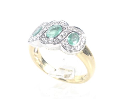 A modern 18ct white and yellow gold, emerald and diamond spiral triple-cluster ring. The three slightly-graduated oval mixed-