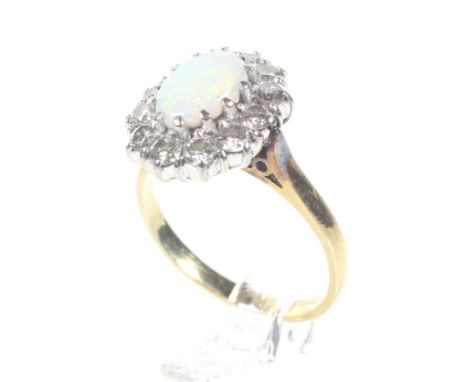 A vintage 18ct gold, opal and diamond oval cluster ring. Centred with an oval cabochon white opal displaying a pleasing play 