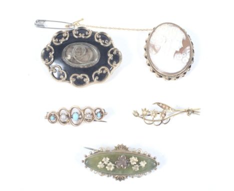 Five Victorian and later brooches. Including a black-enamelled shaped-oval brooch with a central glazed woven hair oval panel