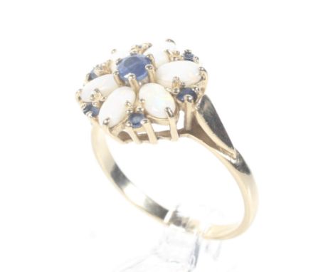 A modern 14ct gold, opal and sapphire cluster ring. Centred with a small round mixed-cut sapphire within an oval-cabochon whi