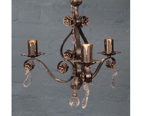 A wrought iron ceiling light with gilt floral decoration and glass droplets.  