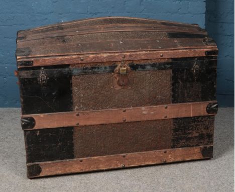 An oak bound dome top trunk, with grape and leaf exterior, brass decoration and liner. Height: 74cm, Width: 94cm, Depth: 55cm