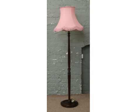 A turned mahogany standard lamp with pink shade