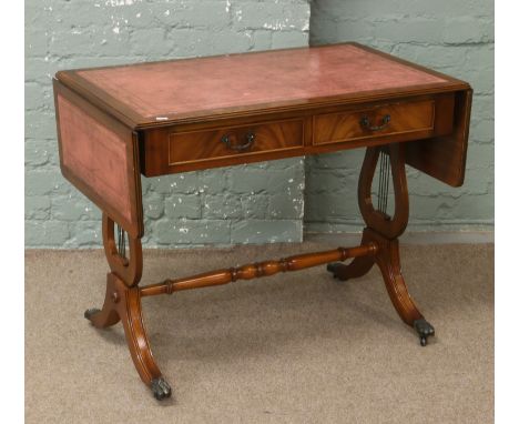 A mahogany sofa table with inset leather top raised over lyre supports raised over brass lion paw casters