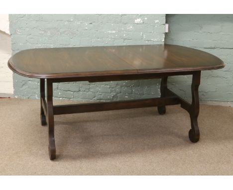 A carved oak extending dining table with bi fold leaf raised on scrolling supports along with a set of four plus two carver a