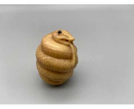 Japanese hand carved tagua nut netsuke of a snake designed with black bead eyes. [4cm] 