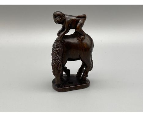 Japanese hand carved netsuke of a monkey sitting on top of a horse. Both designed with black bead eyes and signed by the arti