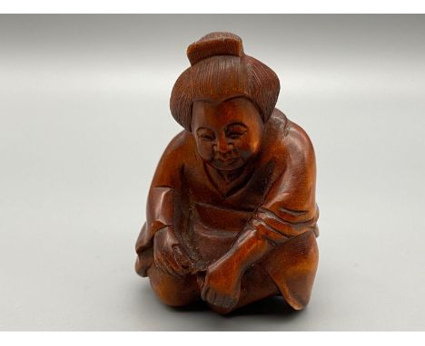A Japanese hand carved netsuke of an elderly Geisha washing her feet. Signed by the artist. 
