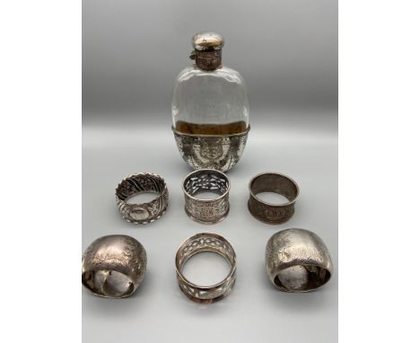 A Lot of 6 various Birmingham silver napkin rings, Together with an ornate plated and glass hip flask. [Total weight of napki