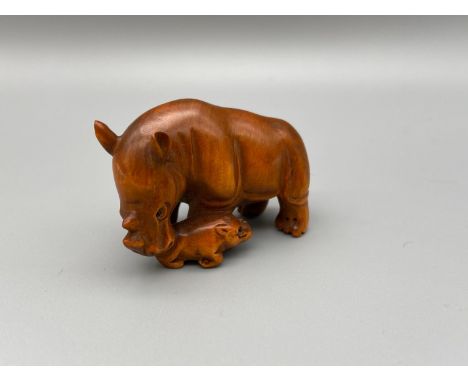 Japanese hand carved netsuke of a mother rhino and baby rhino, both designed with black bead eyes and signed by the artist. [