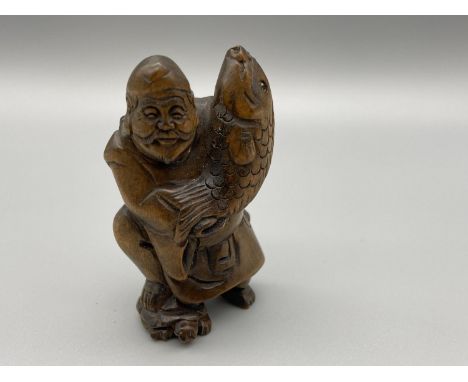 A Hand carved Japanese netsuke figure of a Older Gentleman holding a Koi Carp whilst standing on the shell of a turtle. Carp 