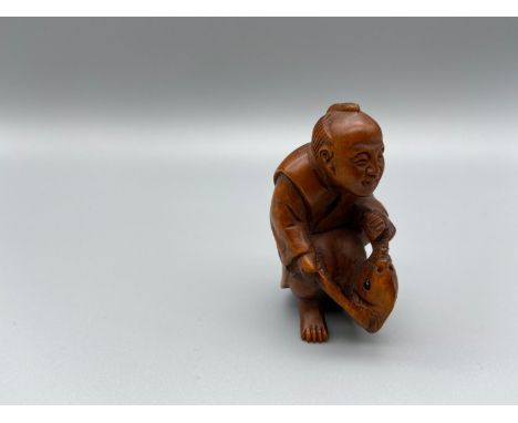 Japanese hand carved netsuke of a gentleman holding a koi carp with black bead eyes, signed by the artist [5cm] 