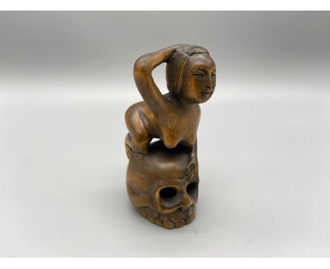 A Japanese hand carved netsuke of a nude geisha laying on top of a skull. Signed by the artist. 