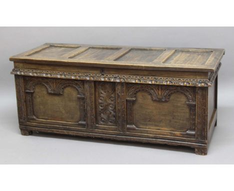 OAK COFFER,  18th century, the four panel cover with pin hinges above a central foliate carved panel flanked by a pair of arc