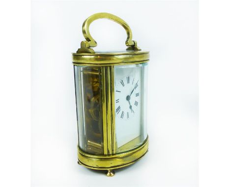 A late, 19th century, polished brass, oval-shaped carriage clock with clear glass panels to each side on four bun feet, with 
