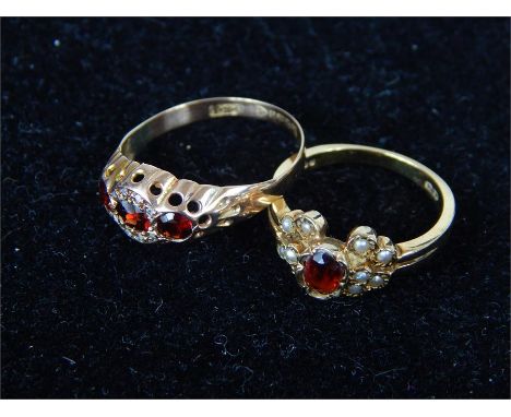 Two 9 ct yellow gold and garnet rings, one centrally set with three, faceted garnets, the central garnet surrounded by a halo