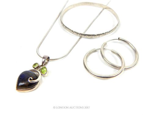 A silver necklace having a labradorite and peridot pendant, together with a bangle and a pair of hoop earrings.